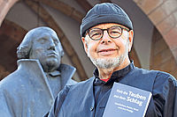 Sehr an Kirchenthemen interessiert: Sprachkünstler Michael Bauer mit seinem neuen Buch vor dem Landauer Luther. Foto: VAN