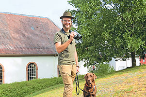 Die Waffe darf er noch nicht tragen: Gemeindepfarrer Christoph Krauth mit Labrador-Hündin Mila. Foto: Kahn